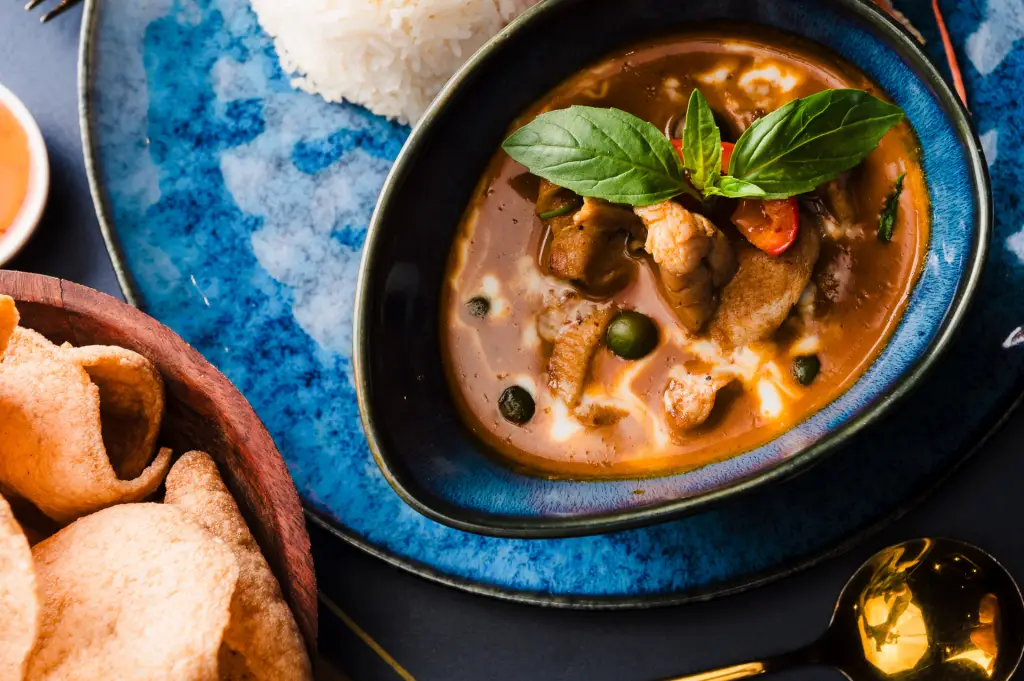 panang curry with a basil garnish and thai prawn crackers
